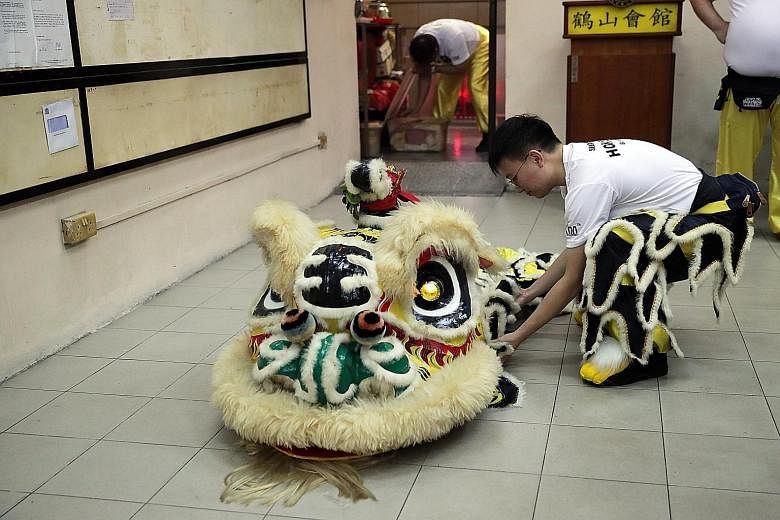 Above: Performer Ho Chin Wah, a civil servant, displaying Singapore's oldest lion head at the association's shophouse premises. The lion head weighs 15kg, compared with modern versions, which weigh only about 1kg. Left: After facing a youth membershi