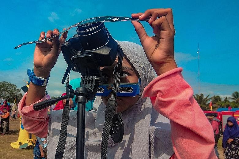 A girl placing a filter in front of her camera to take photos of the annular solar eclipse in Siak, in Indonesia's Riau province, yesterday.