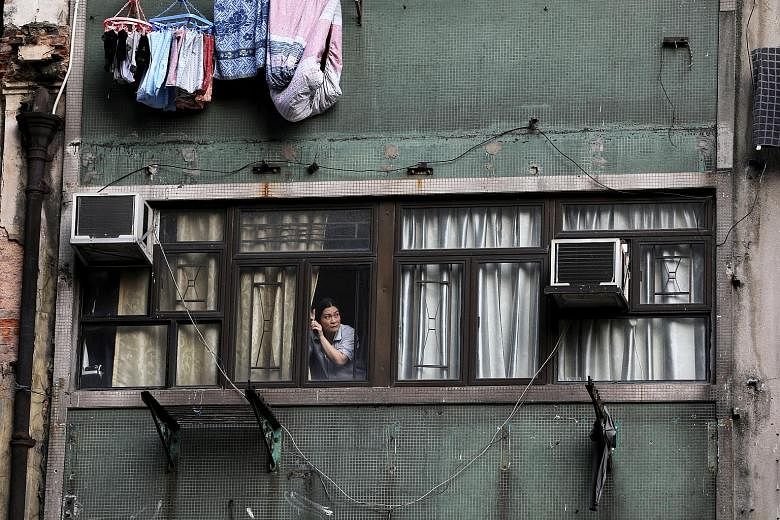 A Hong Kong resident watching anti-government protests from her apartment window in October. The often violent demonstrations have been dragging on, upsetting the lives of the city's residents. Safety concerns, daily inconveniences and economic woes 
