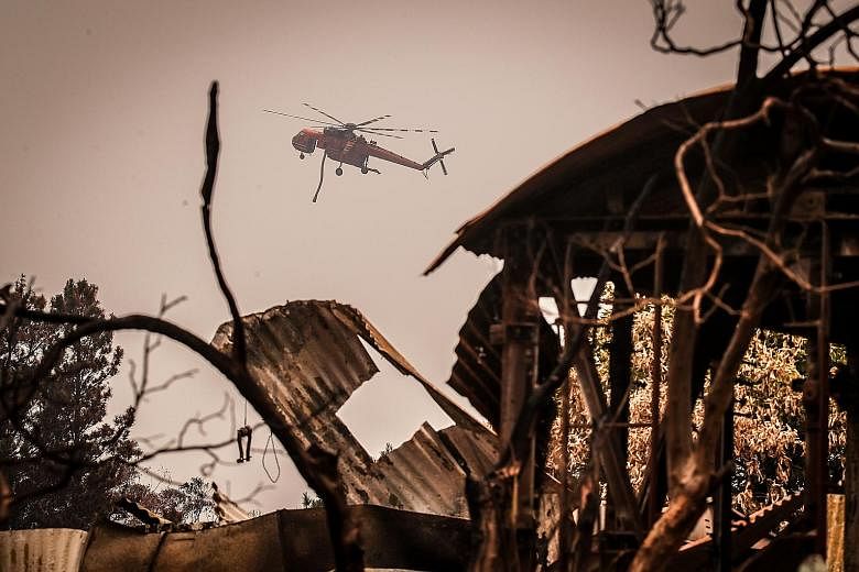 A helicopter with a water hose flying over a house destroyed by bush fires near the town of Bilpin, New South Wales, on Sunday. The state has borne the brunt of the fires, which have burned out more than 2.5 million ha of forest and bush land and des
