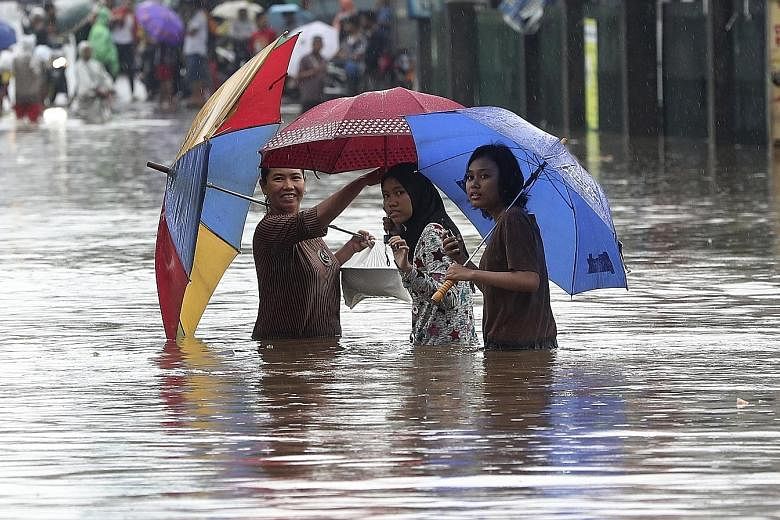 People wading through floodwaters in Jatibening, on the outskirts of Jakarta, yesterday. Electricity was cut off in many of the city's neighbourhoods, with some train lines and an airport also shut.