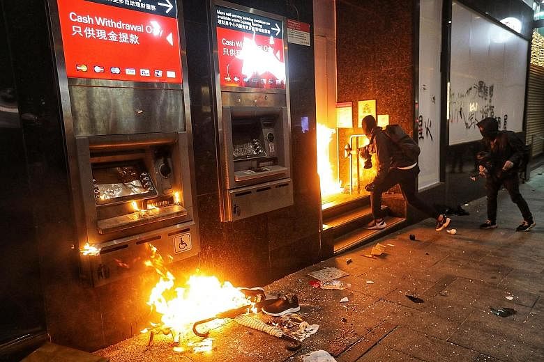 Protesters setting fire to automated teller machines outside a bank during the anti-government rally in Hong Kong yesterday. PHOTO: EPA-EFE Protesters marching in Hong Kong during a massive pro-democracy rally on New Year's Day, looking to carry the 