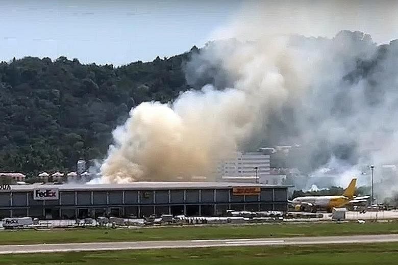 Thick, white smoke billowing from behind the cargo building opposite the runway of Penang airport on New Year's Day. The fire, caused by burning grass, was put out by the airport's firemen. PHOTO: THE STAR/ ASIA NEWS NETWORK