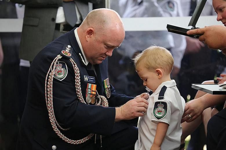 New South Wales' Rural Fire Service Commissioner Shane Fitzsimmons pinning a medal for bravery on 19-month-old Harvey Keaton's shirt during his father Geoffrey Keaton's funeral in Sydney on Thursday.