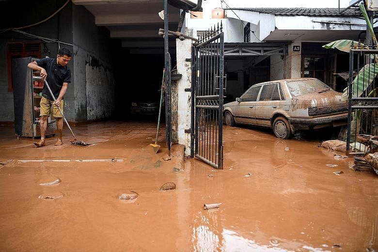 A man sweeping away the mud left by the floods yesterday in a residential area in Bintaro, Jakarta. Emergency response staff have started clearing some access roads to make way for residents to return to their homes. PHOTO: REUTERS Residents cleaning
