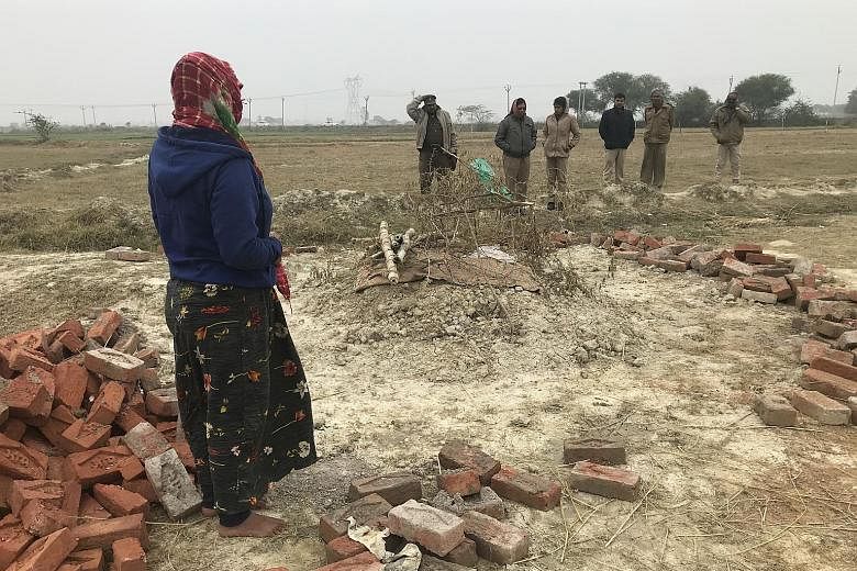 A woman at the grave of her sister who was raped and later set on fire, allegedly by two of her accused rapists, in a village in Unnao. Accompanying her on the visit to the grave were police officials assigned to protect the family. She said her sist