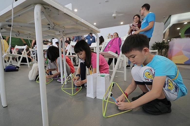 (From right) Siblings Ma Junlong, eight, and Ma Xiangyu, 10, building walking robots at a taster class for Code in the Community's new applications programme at Our Tampines Hub yesterday. The programme will introduce more complex ideas and encourage
