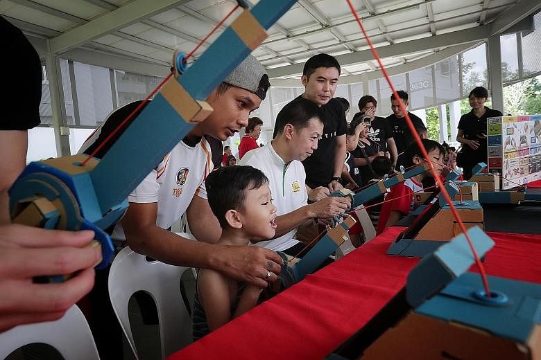 Adviser to Canberra GROs Lim Wee Kiak (seated) trying out a fishing game that uses Nintendo Labo yesterday. The game section was set up by Bountie Technologies as part of a block party organised in conjunction with WeCare @ North West - Service Weeks