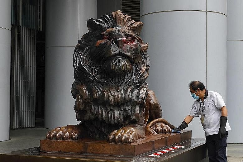 A worker cleaning one of the two iconic HSBC bronze lion statues daubed with red and black paint by protesters in Hong Kong.