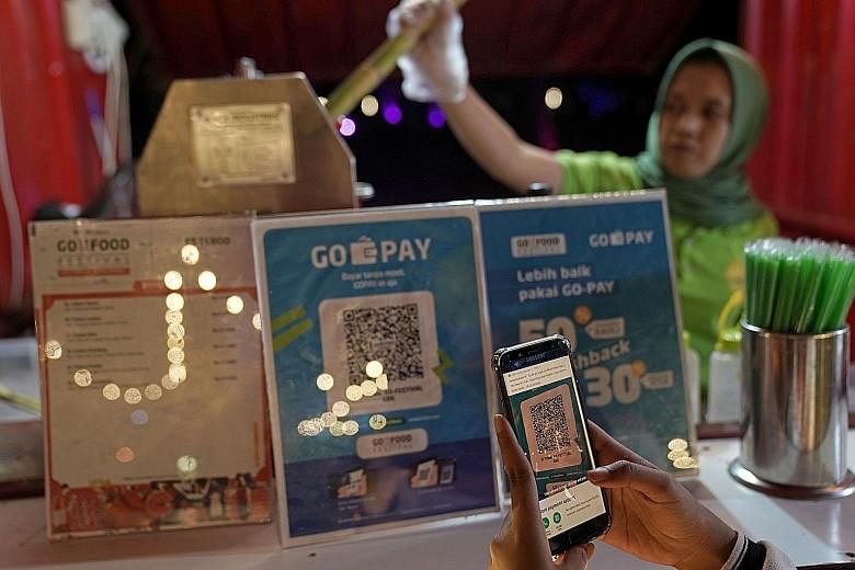 A customer using digital payment at a stall at the Go-Food Festival in Jakarta last year. Financial technology is booming in Indonesia, beginning with digital payments, says the writer, adding that there is a natural synergy of digital payments with 