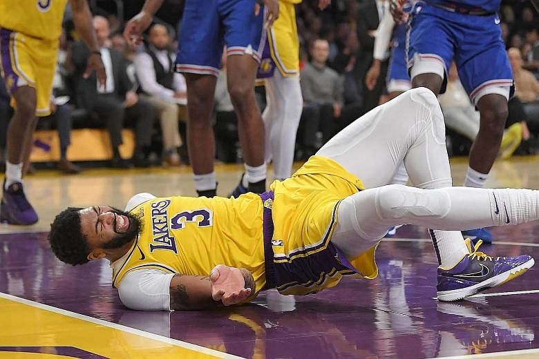 Los Angeles Lakers star Anthony Davis wincing as he hits the court after colliding with Knicks forward Julius Randle in the third quarter of their NBA match. Davis left the game with five points but the Lakers won 117-87. PHOTO: ASSOCIATED PRESS
