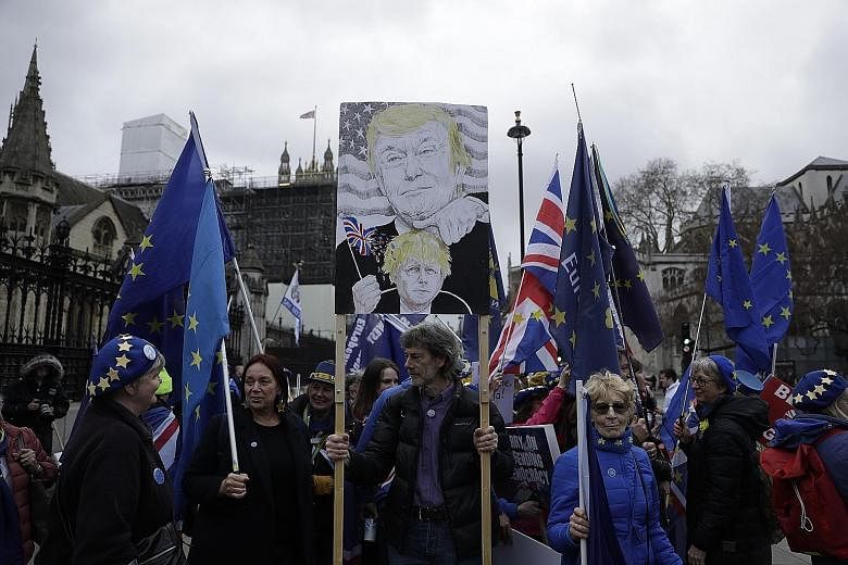Anti-Brexit protesters, including one with a placard depicting British Prime Minister Boris Johnson under the thumb of US President Donald Trump, demonstrating outside the Houses of Parliament in London on Wednesday. British lawmakers on Thursday app