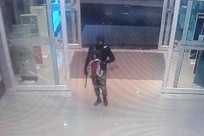 A series of CCTV screen grabs shows a gunman as he enters the Robinson shopping mall, approaches a counter, and then jumps onto it in Lopburi province, Thailand, on Thursday. ,