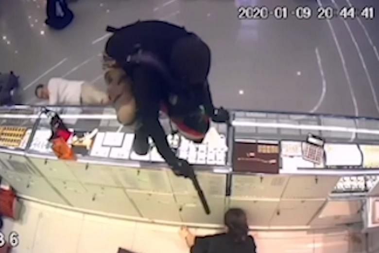 A series of CCTV screen grabs shows a gunman as he enters the Robinson shopping mall, approaches a counter, and then jumps onto it in Lopburi province, Thailand, on Thursday. 