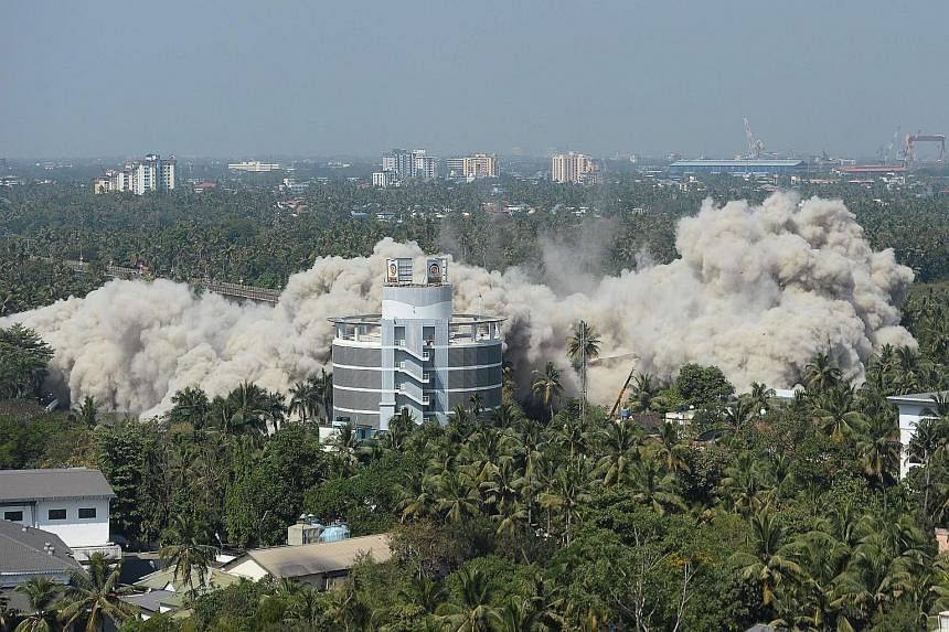An apartment complex in Kerala's Maradu district being demolished yesterday using controlled implosions, after a court last year ordered its demolition for violating coastal construction regulations. Two buildings were razed yesterday and a remaining