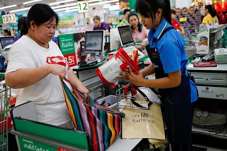 Top left: Banners informing customers about the ban on single-use plastic bags at a shopping mall in Bangkok, as major Thai retailers kicked off the new year with the curbs. Above: A woman using a shopping bag at a shopping centre in Bangkok on Jan 2