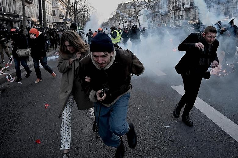 Protesters running away from tear gas during a demonstration last Saturday in Paris, as part as a nationwide multi-sector strike against the French government's move to overhaul the pension system.