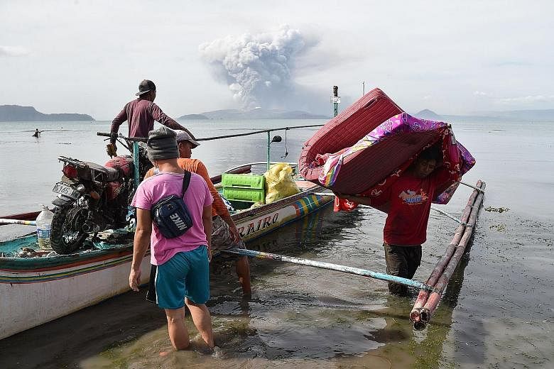 Residents unloading their belongings from a canoe in the town of Tanauan. More than 25,000 people have been evacuated to safer areas, most of them from Batangas province, which yesterday declared a state of emergency. A teenager living at the foot of
