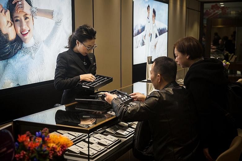 An employee showing jewellery to customers at a Chow Tai Fook store in Hong Kong, in a 2016 file photo. The jeweller plans to close about 15 of its Hong Kong stores, mainly in tourist districts.