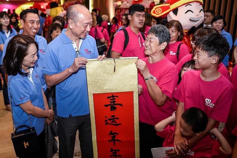 Mr Wee Ee Cheong (second from left), deputy chairman and chief executive of UOB, and Mrs Wee, seen here with Mr Eric Tham (back row, far left), head of UOB's group commercial banking, presenting a Chinese calligraphy scroll for Chinese New Year to a 