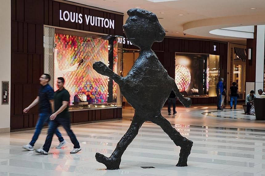 The Aventura Mall in Florida invites children and adults to take rides on its nine-storey slide (left) and has installed whimsical sculptures such as the Walking Figure (below). It emphasises low-tech entertainment over cutting-edge gadgetry to beat 