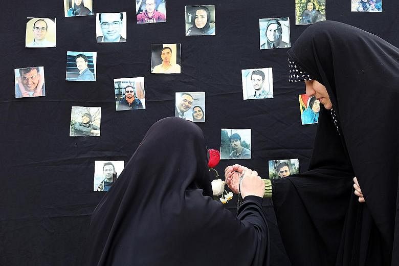 Part of the wreckage of the Ukrainian plane that was shot down outside Teheran on Jan 8, killing all 176 people on board. PHOTO: AGENCE FRANCE-PRESSE Iranian students lighting a candle during a memorial ceremony in Teheran on Tuesday for the passenge