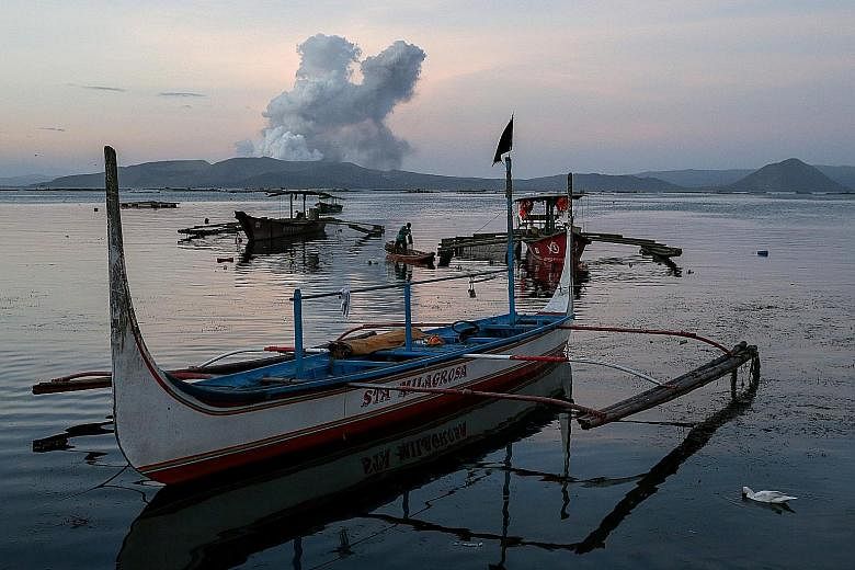 A fisherman at work as the Taal volcano in the Philippine province of Batangas shuddered continuously with quakes yesterday. Officials have warned people against speculating that the five-day eruption is waning.