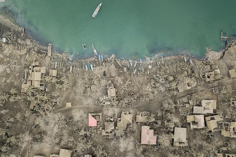 Residents affected by the eruption of the Taal volcano at an evacuation centre yesterday in Tagaytay City, in the Philippine province of Cavite, which has been placed under a state of emergency. An aerial view of buildings covered in ash from the Taa