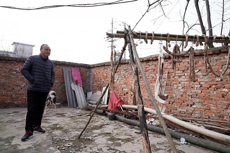 Chinese villager Xu's husband in their yard, where la rou and homemade sausages are strung up. African swine fever has decimated pig herds in China, with pork prices tripling from a year ago due to the shortage.