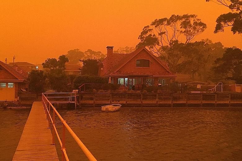 The view of the jetty from the writer’s family house in Merimbula on a clear day and the house (above) being engulfed by smoke and ash from the bushfires.