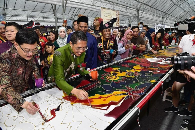 (From left) Deputy Prime Minister Heng Swee Keat and Mayor of South East District and adviser to Wisma Geylang Serai, Dr Maliki Osman, at the Community Batik Record challenge during the first anniversary celebration of the Wisma Geylang Serai yesterd