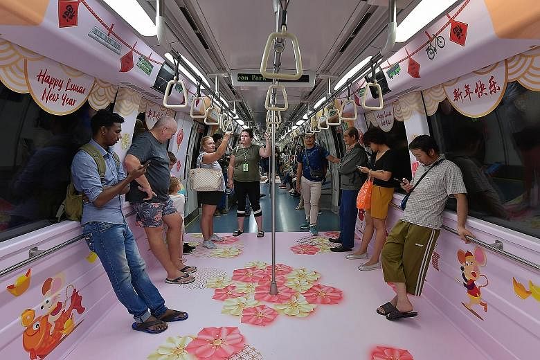 Commuters on a North East Line train decked out in Chinese New Year-themed designs. One train on each of Singapore's five rail lines will be decorated with motifs of the Chinese zodiac animals, flowers and gold ingots until Feb 15. Several buses will