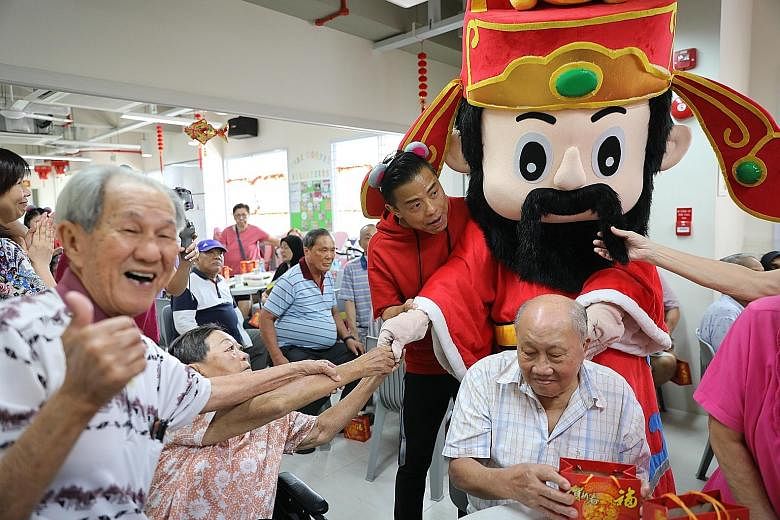 Mr Teo Kiong Chiang (left), 81, a senior at Care Corner Senior Activity Centre, gives the thumbs up as the God of Fortune distributes oranges to the elderly. The man dressed as the God of Fortune is 48-year-old Andrew Lum, SPH's assistant manager of 