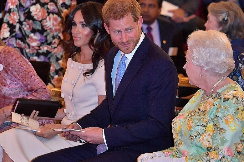 A 2018 photo of Britain's Queen Elizabeth with Prince Harry and his wife Meghan at a Buckingham Palace reception.