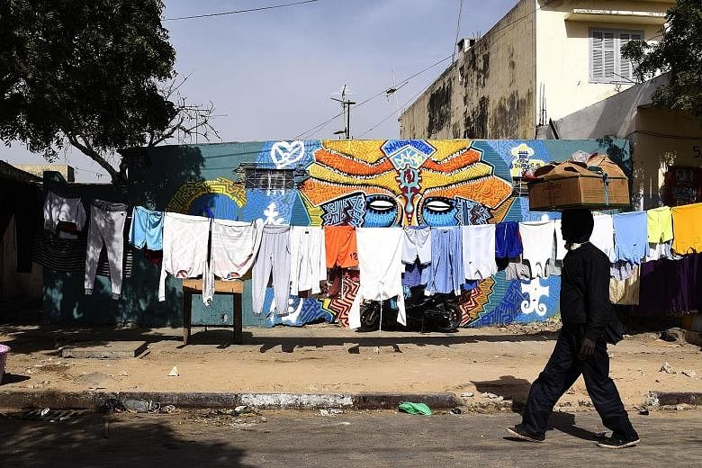 Wet laundry dry in the sun alongside colourful wall murals in Dakar's working-class Medina neighbourhood.