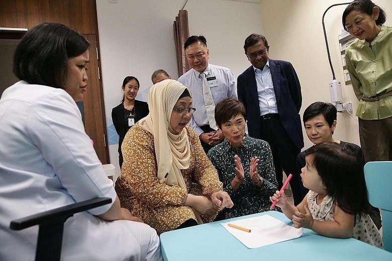 Parents queueing to have their children immunised at the Temasek Foundation Integrated Maternal and Child Wellness Hub yesterday. Minister for Manpower and Second Minister for Home Affairs Josephine Teo applauding as Madam Radina Roslan and her 21-mo