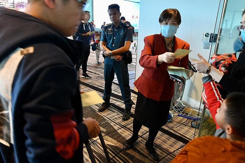 Health advisory pamphlets being distributed at Changi Airport yesterday to passengers who had just disembarked from a flight from Hangzhou, in Zhejiang province. Those who are sick are urged to act responsibly by putting on a face mask to capture the