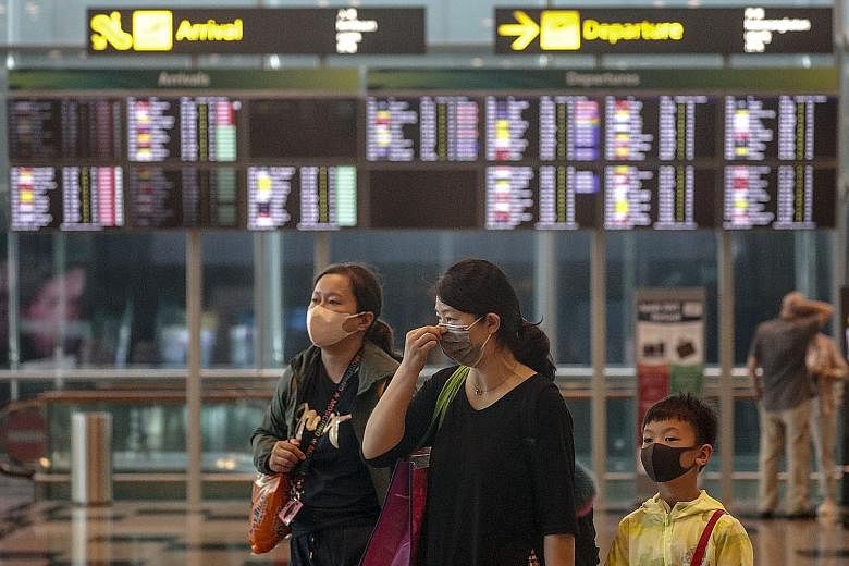 A family donning masks at Changi Airport yesterday. There is widespread concern that travel in and out of China during the upcoming Chinese New Year holiday could allow the mystery Wuhan virus to spread even further and faster.