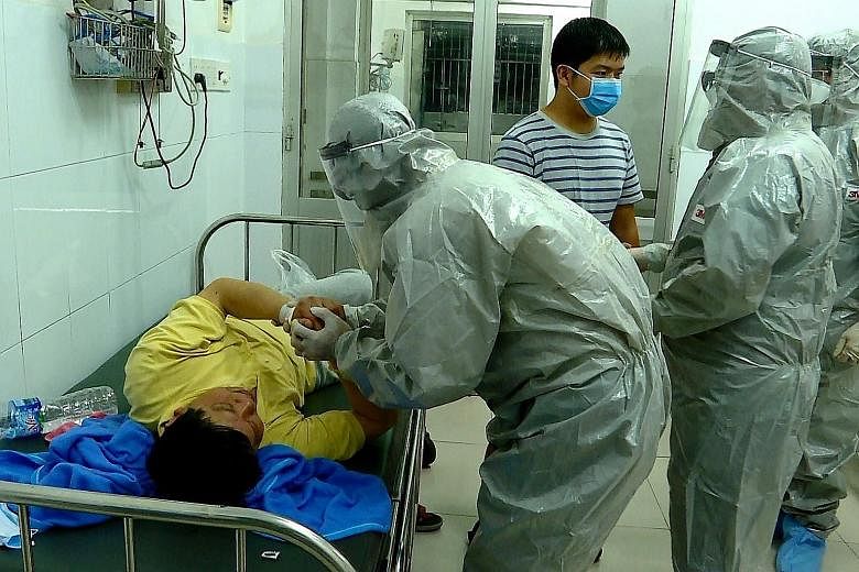 Officials from Vietnam's Ministry of Health talking to a man who tested positive for the Wuhan coronavirus in an isolated area of Cho Ray hospital in Ho Chi Minh City on Thursday.