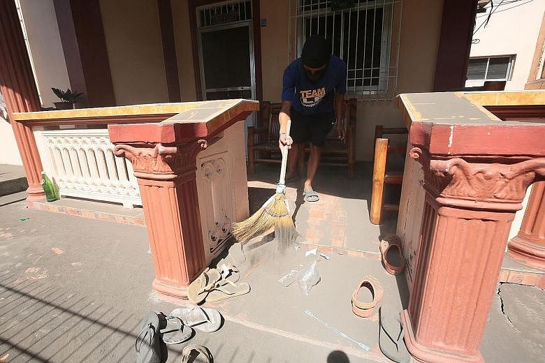 A resident cleaning ash from the front of his home in the town of Lemery, Batangas province, after the Philippine authorities allowed residents to return home yesterday.