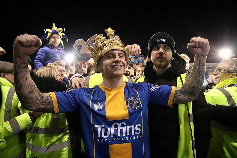 Left: Jason Cummings, Shrewsbury's two-goal hero, is crowned after the 2-2 draw in the FA Cup fourth round, as stewards prevent ecstatic fans from mobbing him. PHOTO: REUTERS Below: Curtis Jones putting runaway Premier League leaders Liverpool 1-0 up