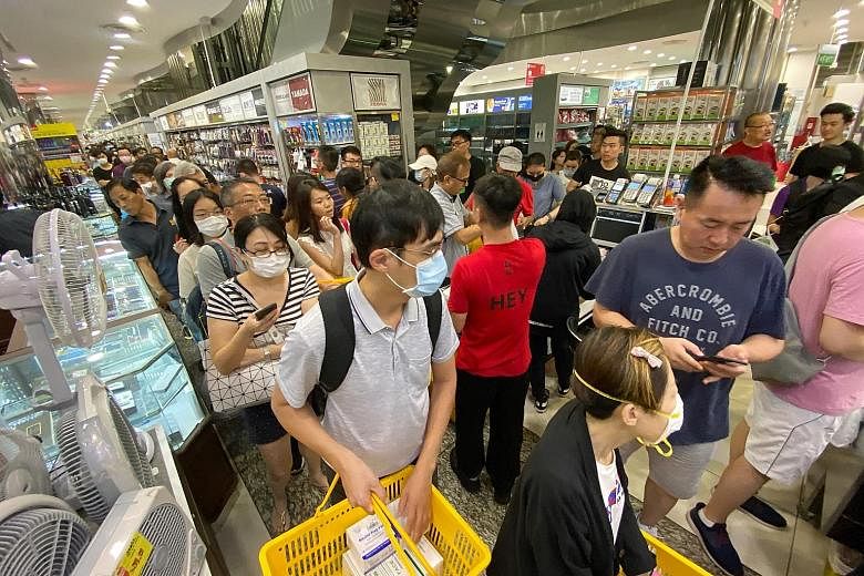 People queueing to buy boxes of masks at Mustafa Centre yesterday. Senior Minister of State for Health Lam Pin Min said there are enough masks if people use them sensibly.