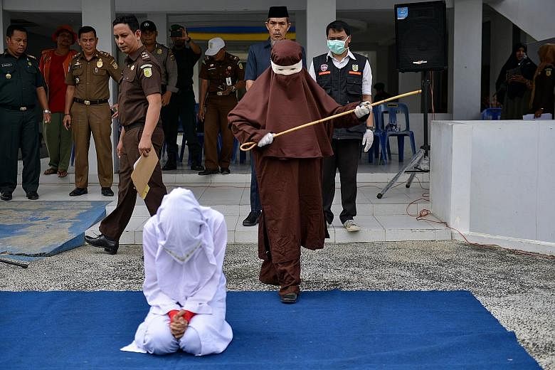 A member of the first female flogging squad in Indonesia's Aceh province preparing to whip a woman last month. Public whipping is a common punishment in the province for premarital sex, adultery, drinking alcohol, gambling and other behaviour that co
