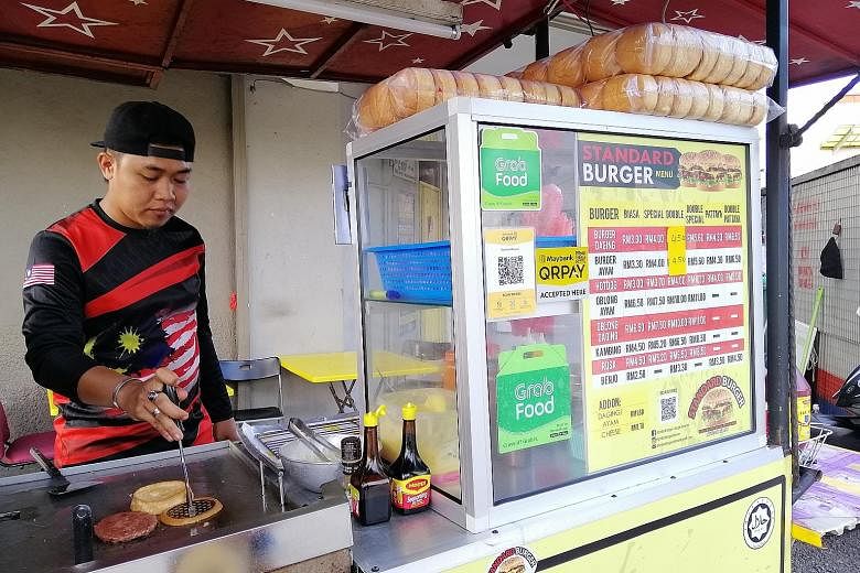 A roadside burger stall in Kuala Lumpur that accepts e-wallet payments. As part of its drive to promote e-payments, the Malaysian government is collaborating with GrabPay, Touch 'n Go eWallet and Boost to give RM30 worth of free shopping money for ea