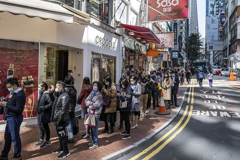 People queueing to purchase protective masks in Hong Kong yesterday. Concerns about the virus prompted shoppers to sweep not just surgical masks, disinfectant wipes and hand sanitisers off the shelves, but also instant noodles and frozen food as peop