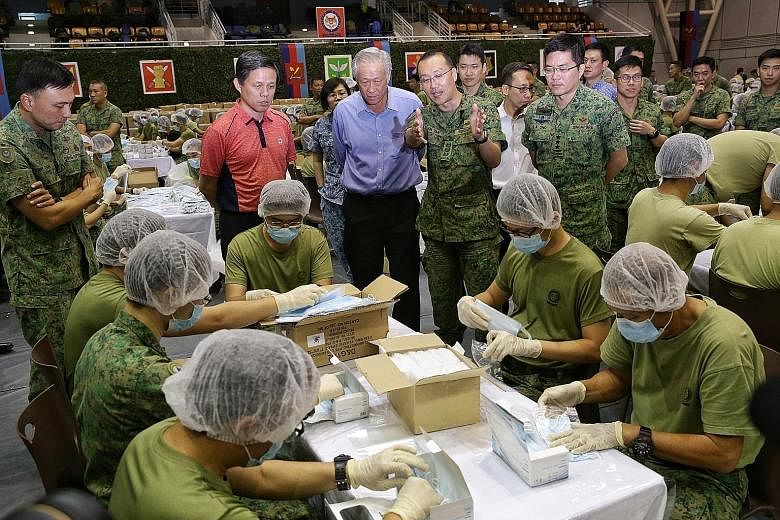 Above: Around 1,500 Singapore Armed Forces servicemen are working round the clock to ensure that the 5.2 million masks are packed in time. In the foreground are sealed boxes containing the packed masks. Left: Trade and Industry Minister Chan Chun Sin