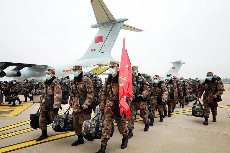 People's Liberation Army medical personnel arriving at Wuhan Tianhe International Airport yesterday. Some 1,400 military medics will be deployed at a new 1,000-bed hospital in Wuhan.