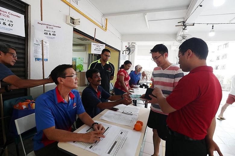 Social and Family Development Minister Desmond Lee (in red) visiting a mask collection counter manned by volunteers at the residents' committee centre at Block 47 Telok Blangah Drive yesterday. Distribution of the masks began on Saturday and will end