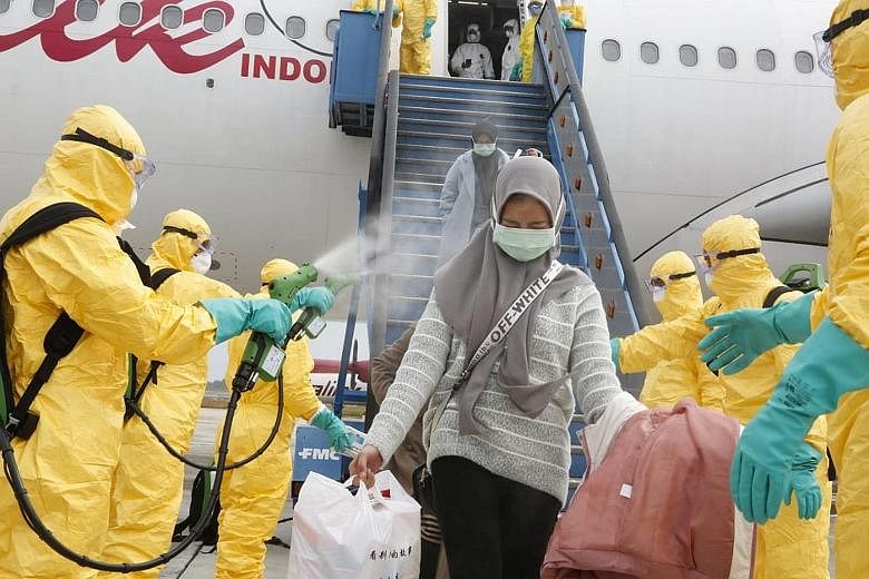 Indonesian nationals being sprayed with antiseptic upon arrival yesterday at Batam's Hang Nadim Airport from the Chinese city of Wuhan, before being taken to the Natuna Islands military base to be quarantined. PHOTO: REUTERS