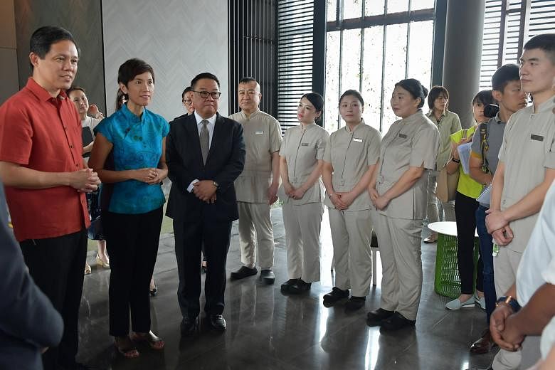 Trade and Industry Minister Chan Chun Sing (left), Manpower Minister Josephine Teo and Far East Hospitality chief executive Arthur Kiong with staff of Oasia Hotel Downtown yesterday. The ministers inspected precautionary measures at the hotel where a